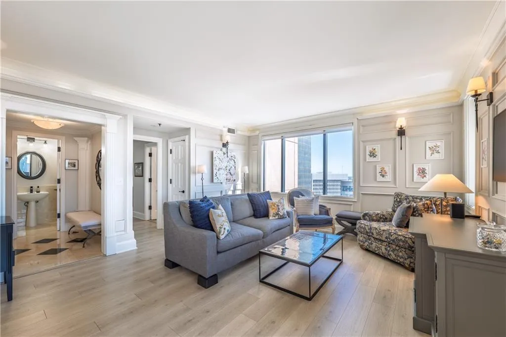Living area featuring light wood-type flooring, visible vents, a decorative wall, and crown molding