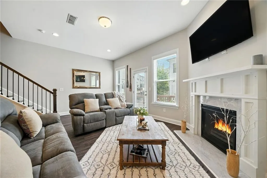 Living room with wood finished floors, recessed lighting, a premium fireplace, and stairs