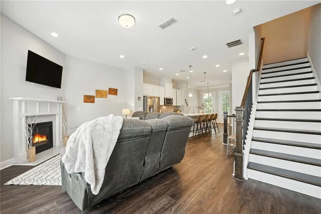Living room featuring stairway, recessed lighting, dark wood-style flooring, and a fireplace
