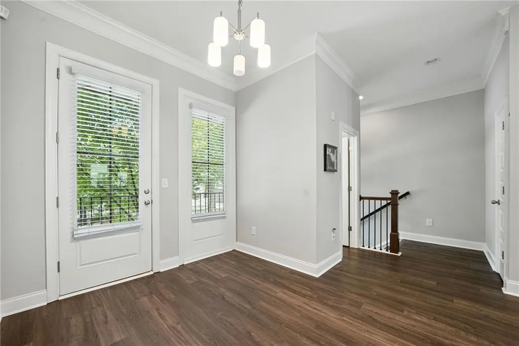 Doorway to outside featuring a chandelier, wood finished floors, and crown molding