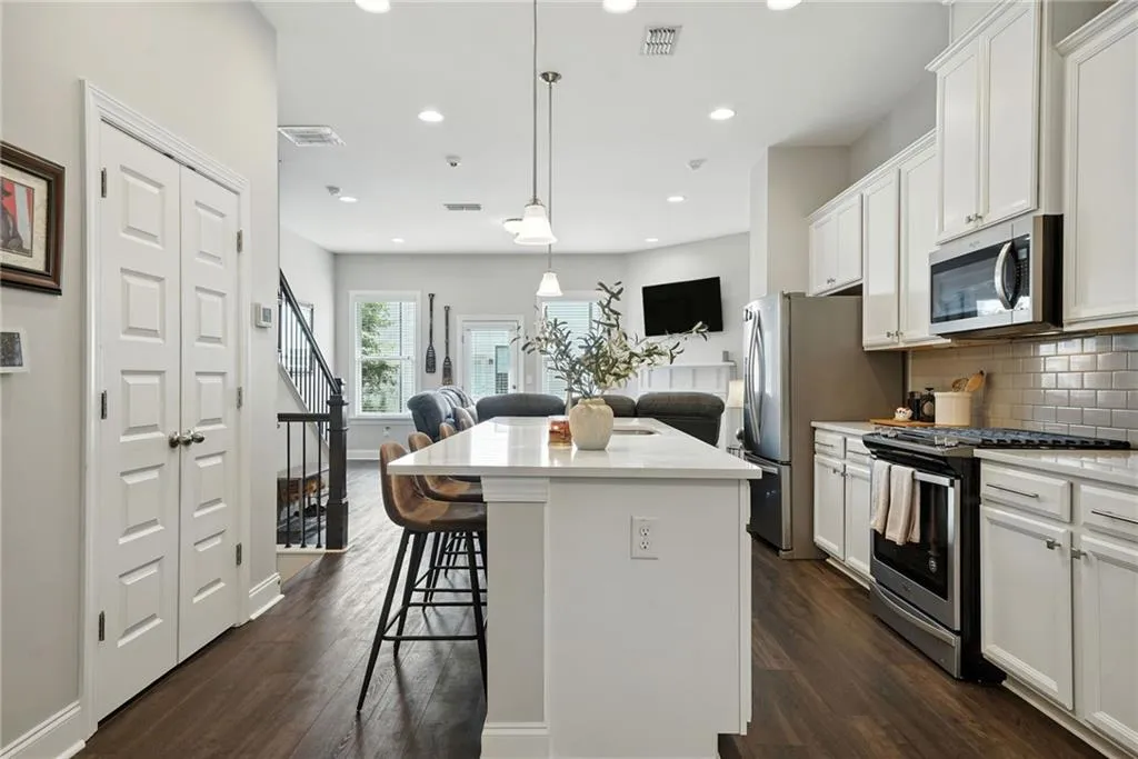 Kitchen featuring appliances with stainless steel finishes, backsplash, white cabinetry, a breakfast bar area, and a kitchen island