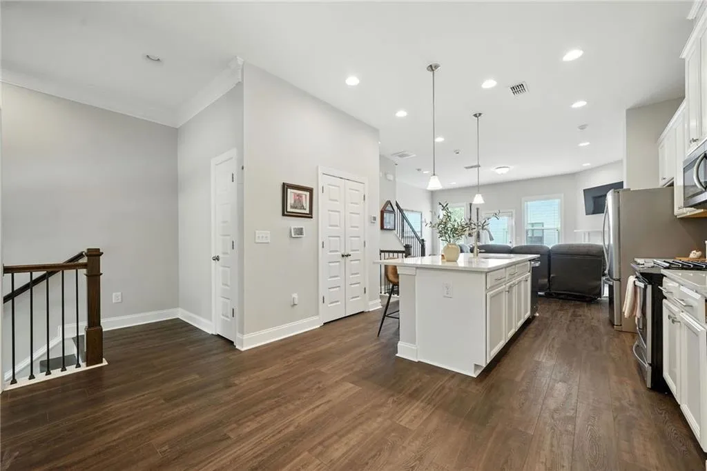 Kitchen with a center island with sink, a kitchen breakfast bar, white cabinets, stainless steel appliances, and recessed lighting