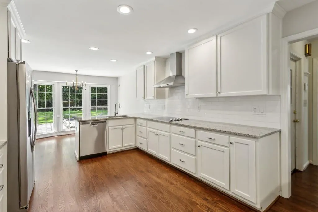 Chef's Kitchen is an absolute showstopper, featuring Stainless Steel Appliances, Granite Countertops, a Classic White Subway Tile Backsplash, Ceiling-Height White Cabinets, a Breakfast Bar, and a Charming Bay Window Breakfast Nook