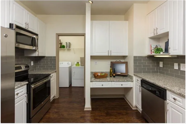 Kitchen with dark wood-type flooring, washer and dryer, white cabinets, and stainless steel appliances