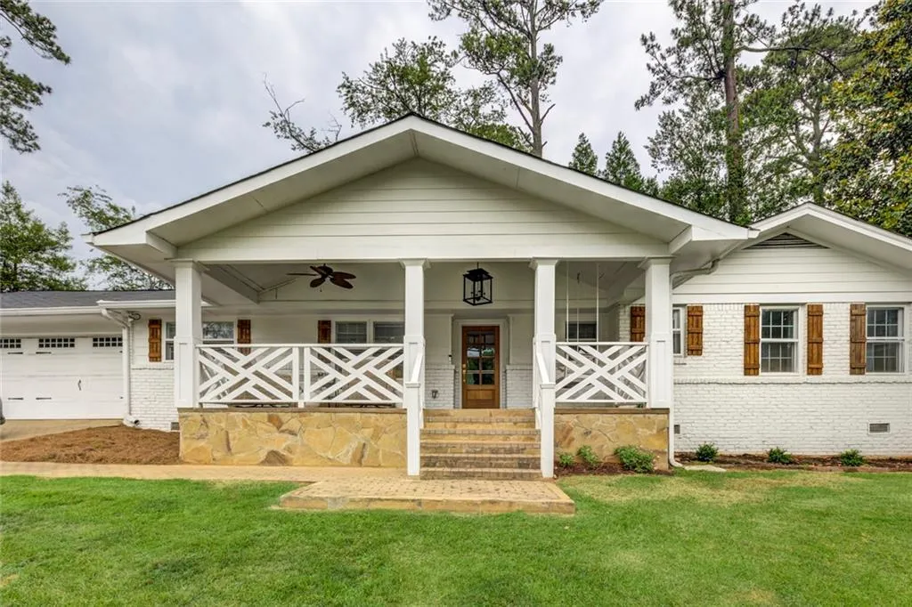 View of front of house featuring a front lawn, a garage, ceiling fan, and covered porch