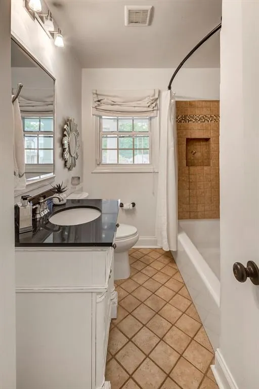 Full bathroom featuring shower / bathtub combination with curtain, tile flooring, toilet, and vanity with extensive cabinet space