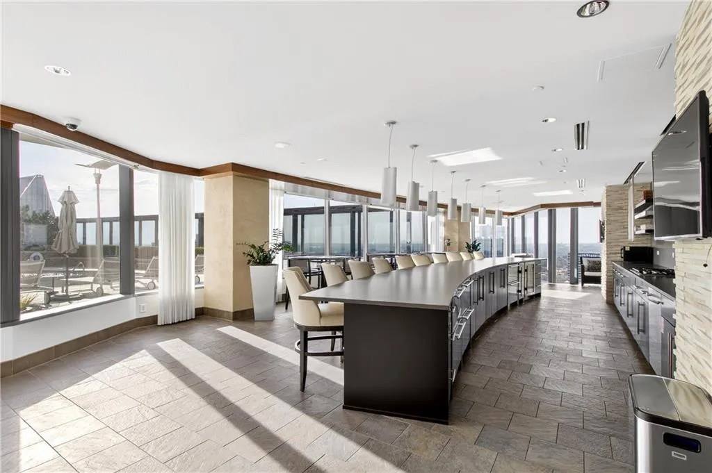 Kitchen with a kitchen bar, dark cabinets, decorative light fixtures, and a spacious island