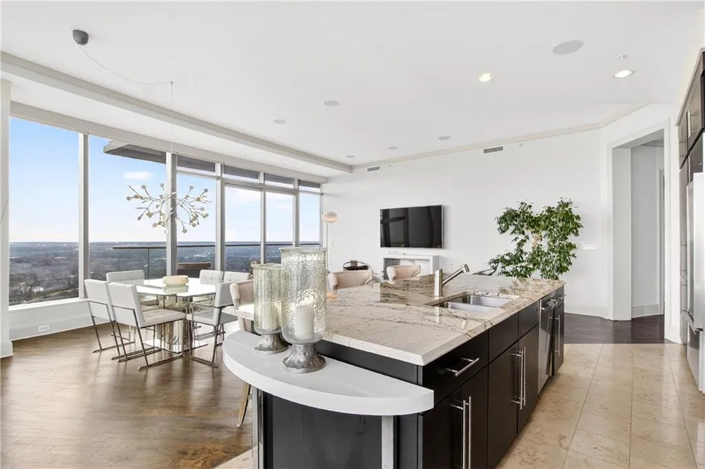 Kitchen featuring dark cabinetry, light stone countertops, open floor plan, a kitchen breakfast bar, and an island with sink