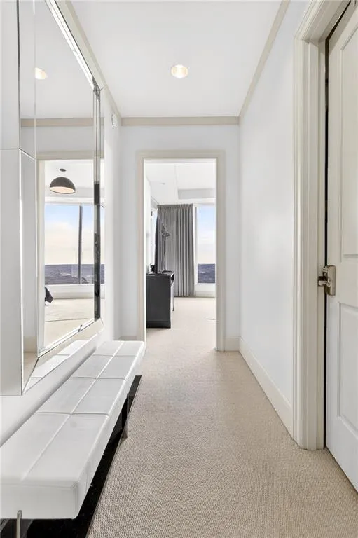Hallway with carpet floors and crown molding