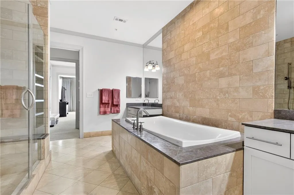 Full bath featuring a tile shower, a garden tub, light tile patterned floors, tile walls, and vanity