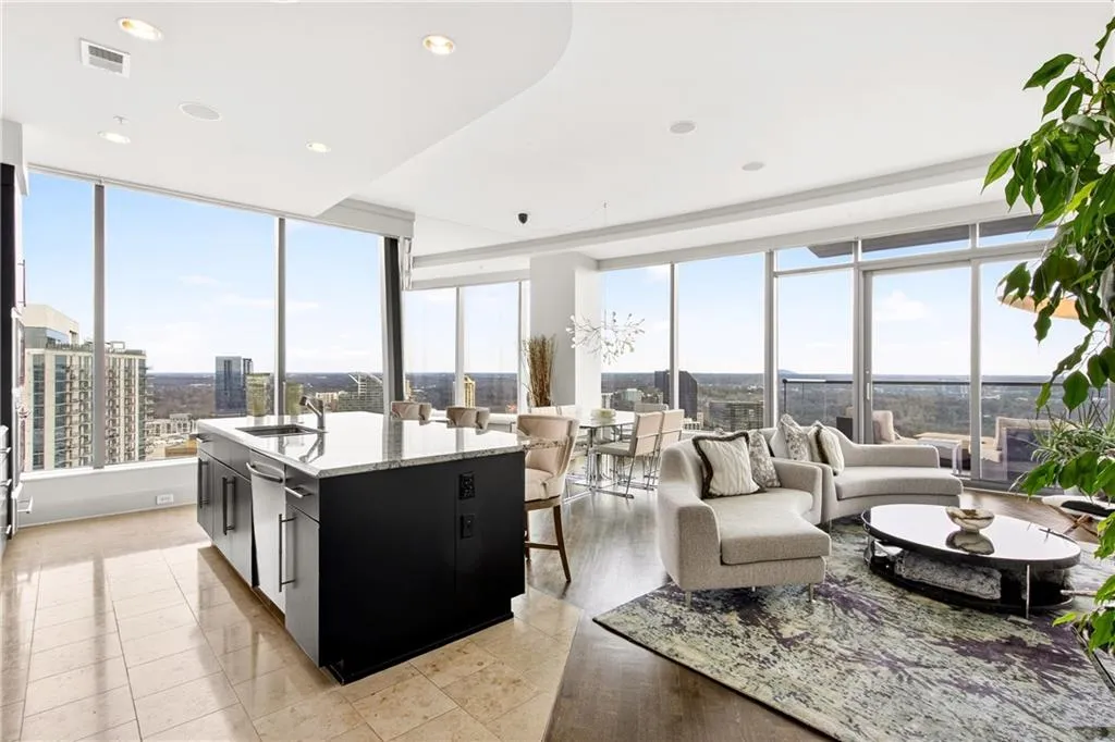 Kitchen featuring dark cabinetry, a kitchen breakfast bar, a kitchen island with sink, light stone countertops, and open floor plan
