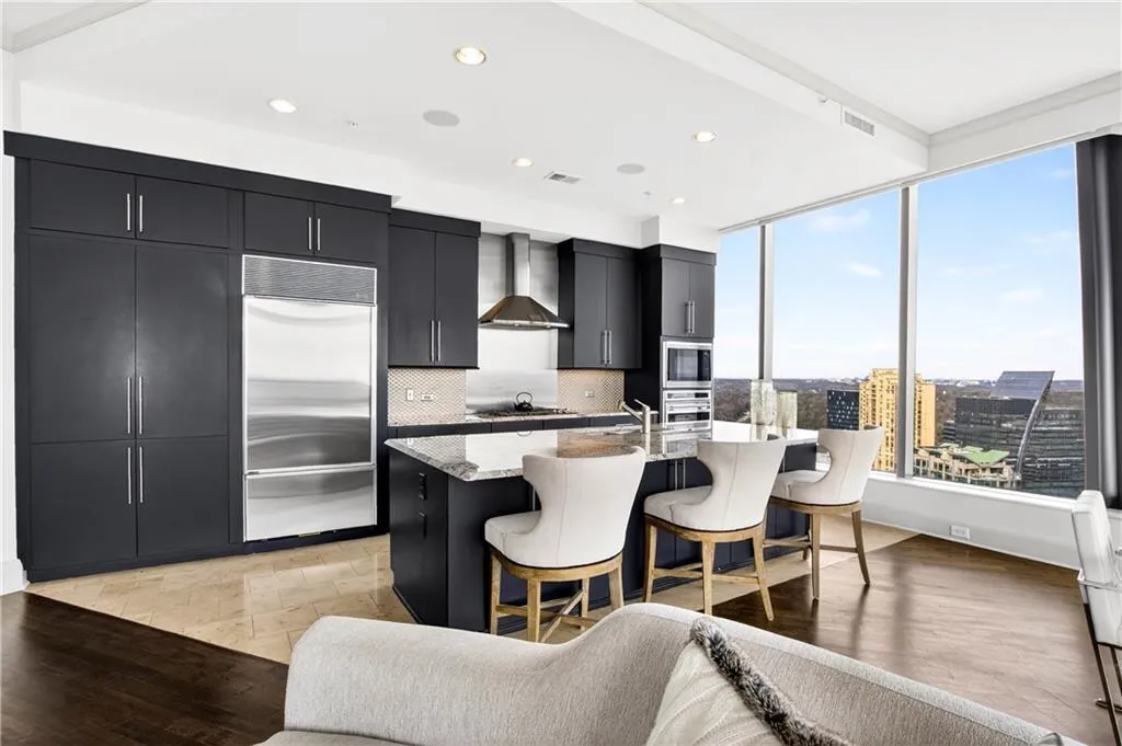 Kitchen with dark cabinets, light wood-style flooring, a breakfast bar, built in appliances, and tasteful backsplash