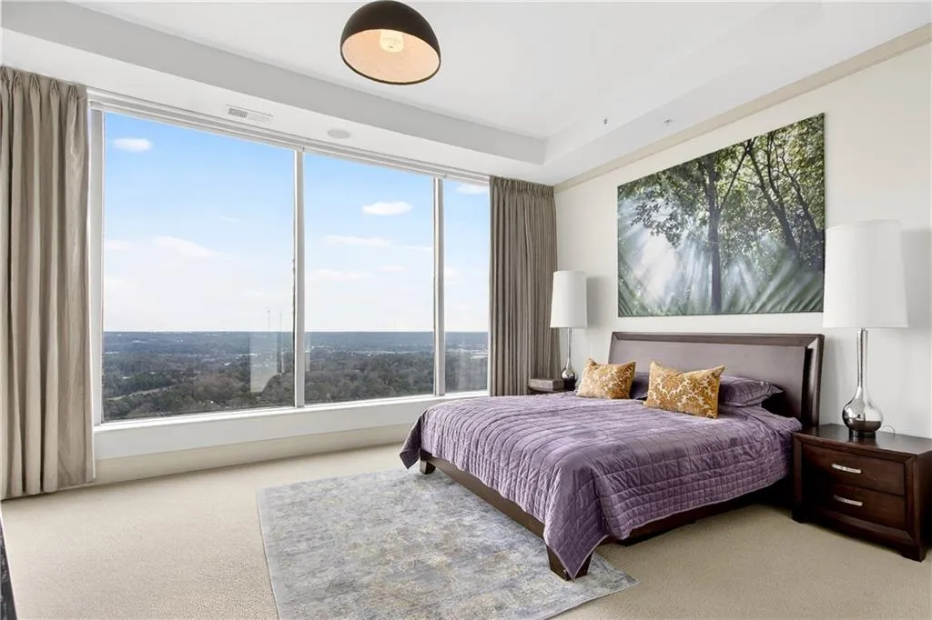 Carpeted bedroom featuring multiple windows and a raised ceiling
