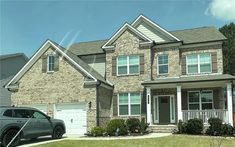 Craftsman inspired home with covered porch, a garage, brick siding, and roof with shingles