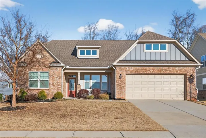Craftsman-style home featuring a shingled roof, concrete driveway, brick siding, and covered porch