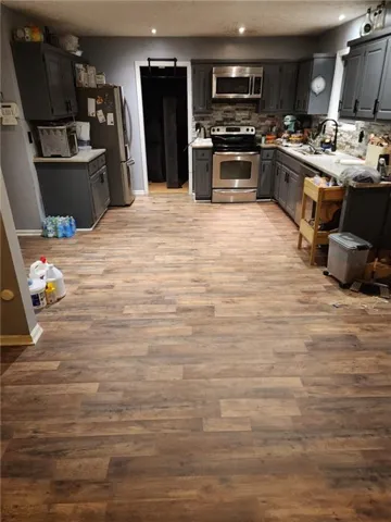 Kitchen featuring gray cabinets, stainless steel appliances, light countertops, recessed lighting, and light wood-style floors