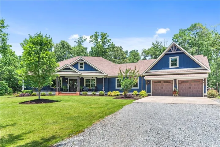 Blue exterior siding with white trim, a covered front porch, and a two-car garage with wood-finish doors