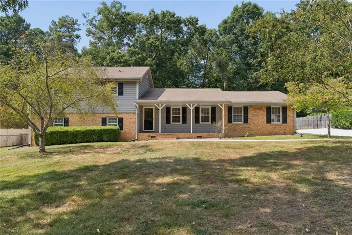 Brick and siding exterior with a covered front porch and mature trees