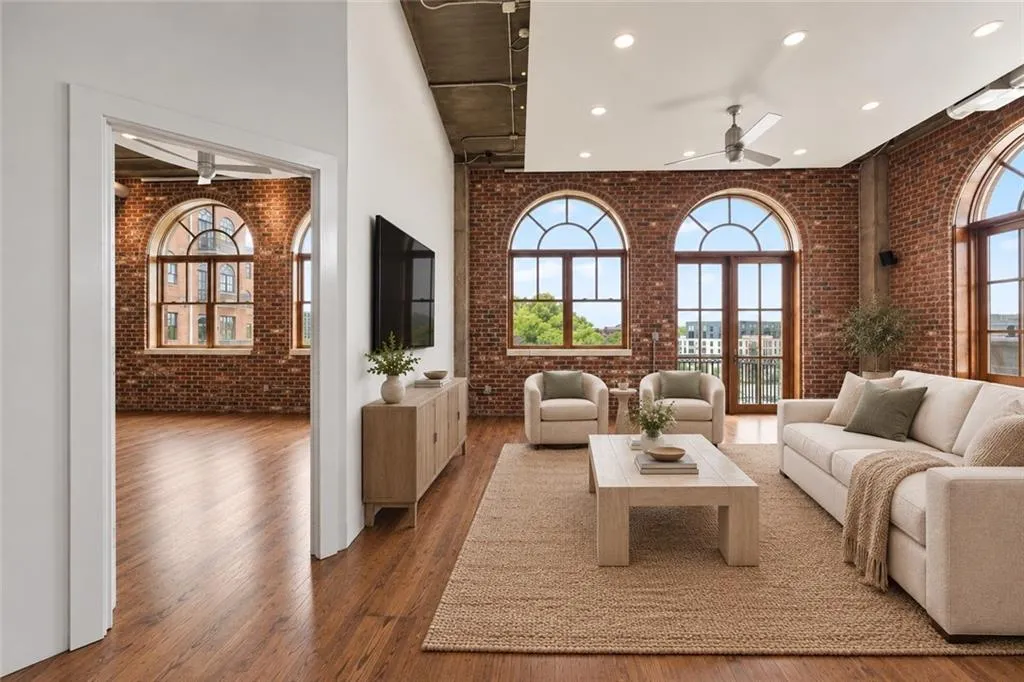 Exposed brick walls, arched windows, wood-finish flooring, high ceilings with industrial-style exposed ductwork, and recessed lighting. Virtual staging.