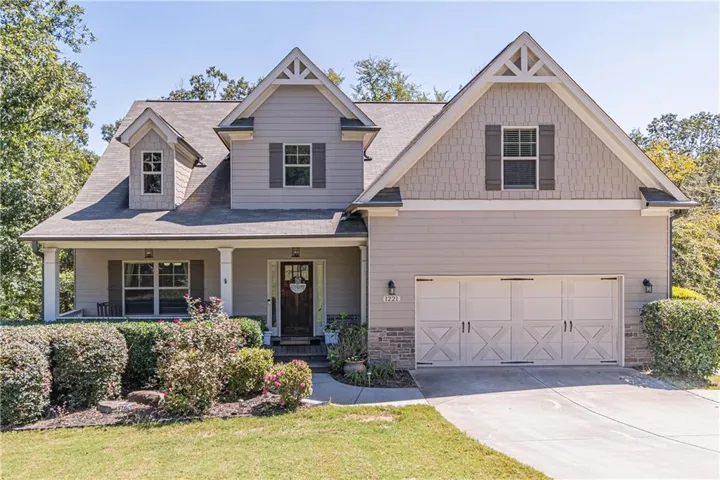 Craftsman-style exterior with a covered front porch, stone accents, decorative gable brackets, and a two-car garage with carriage-style doors