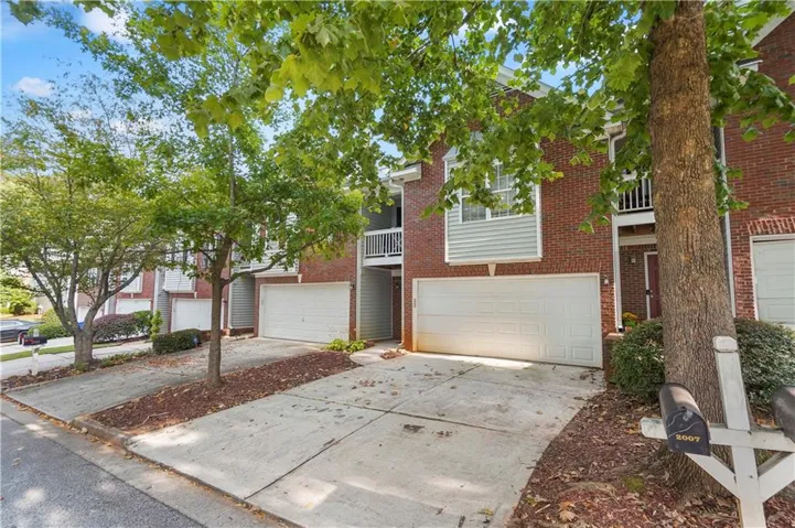 Brick exterior with light gray siding accents, white garage doors, and a concrete driveway
