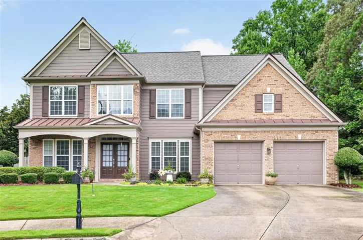 Brick and siding exterior featuring a covered front entry with columns, double front doors, a two-car garage, and a concrete driveway