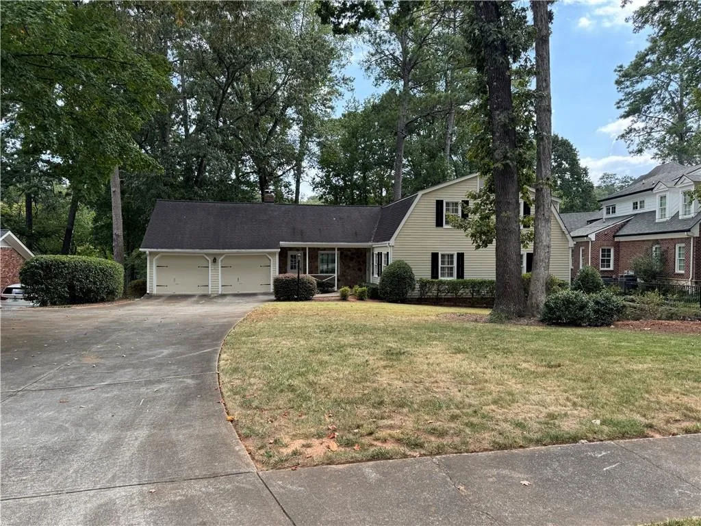 View of front facade with a gambrel roof, covered porch, driveway, a garage, and a front yard