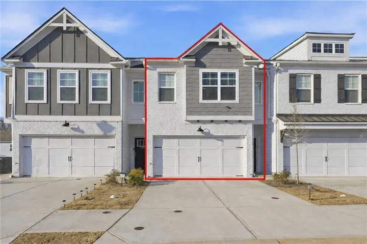 View of front of property with board and batten siding, concrete driveway, a garage, and brick siding