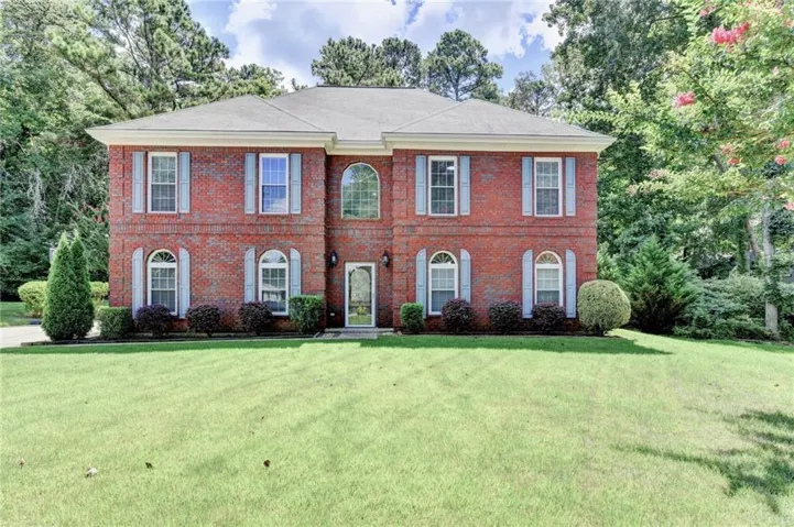 Brick facade with arched windows, light-colored shutters, and a central arched entry