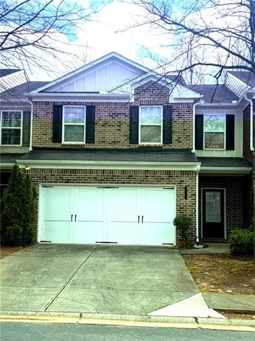 Traditional-style home with a garage, concrete driveway, and brick siding
