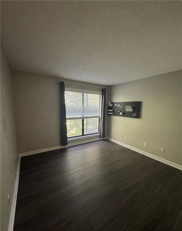 Unfurnished room with a textured ceiling and dark wood finished floors Unfurnished room with a textured ceiling and dark wood finished floors