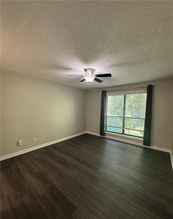 Spare room with dark wood finished floors, a textured ceiling, and ceiling fan Spare room with dark wood finished floors, a textured ceiling, and ceiling fan