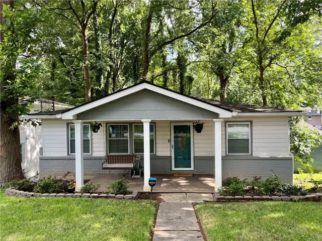 Ranch-style exterior with a covered porch, white siding, and a gray brick foundation