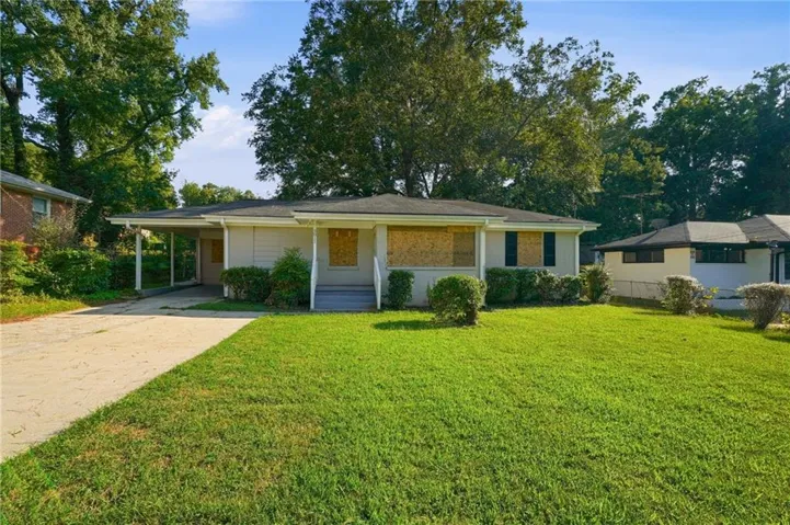 Single-story residence featuring a carport, front porch, and mature landscaping