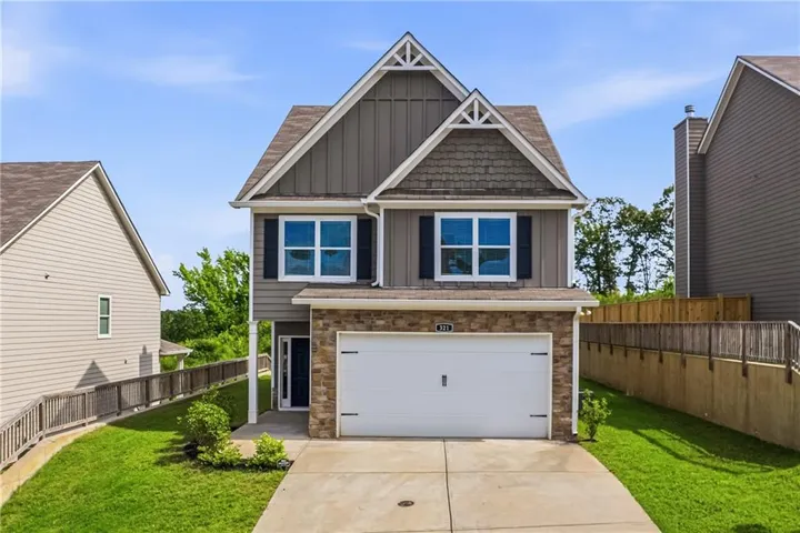 Two-story residence featuring a stone and siding facade, a two-car garage, and a concrete driveway