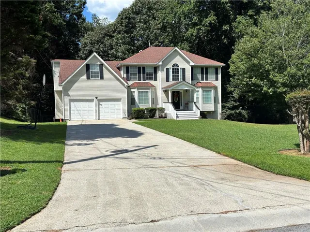 Traditional two-story residence with a covered front entry, bay window, two-car garage, and established landscaping