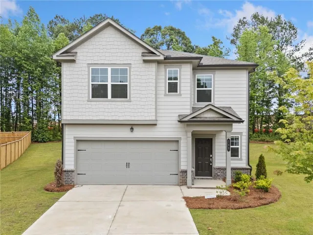 Two-story residence featuring light gray siding, a covered entry, an attached two-car garage, and established landscaping