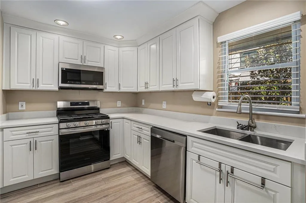 Kitchen featuring stainless steel appliances, a sink, white cabinetry, light countertops, and recessed lighting