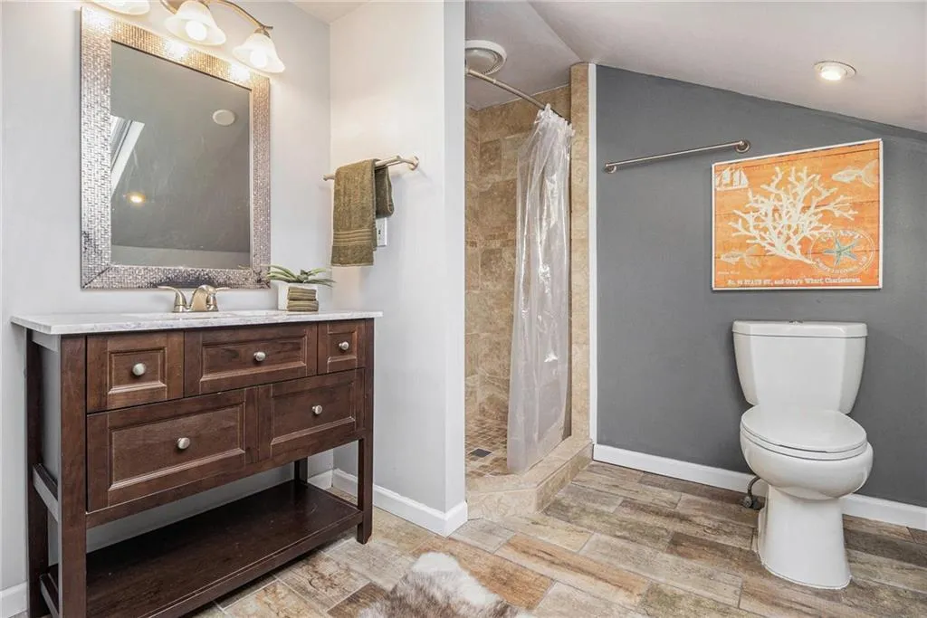 Full bath with a tile shower, toilet, vanity