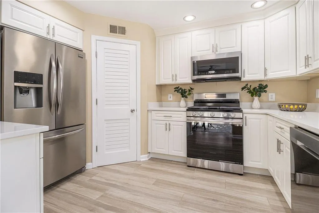 Kitchen featuring stainless steel appliances, white cabinets, light countertops, recessed lighting