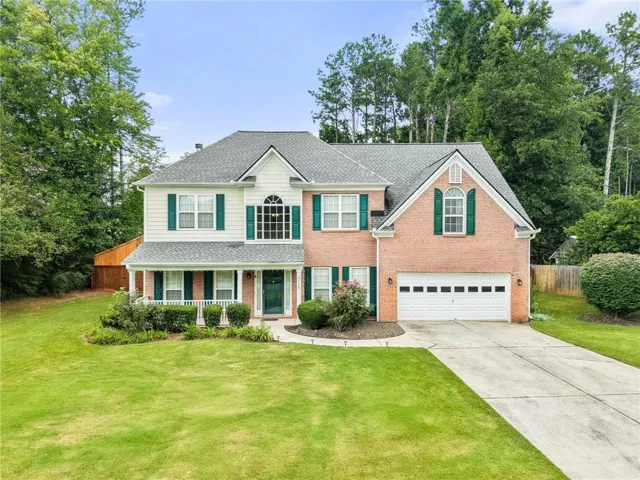 Traditional two-story residence featuring brick and siding facade, a covered front porch, and a two-car garage