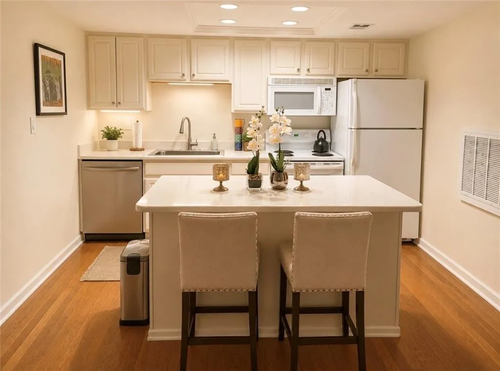 Kitchen featuring a central island with countertop seating, white cabinetry, recessed lighting, wood-finish flooring, and a stainless steel dishwasher