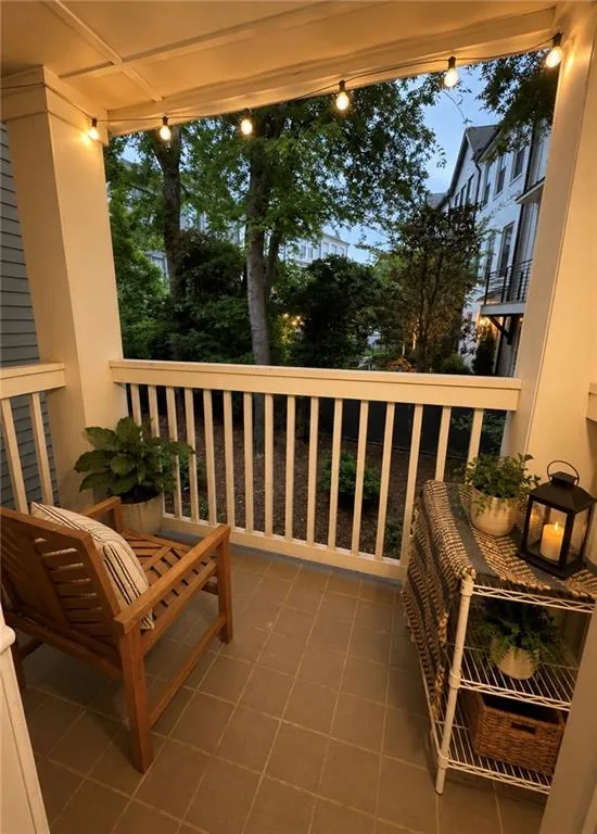Covered porch featuring string lighting, tile flooring, and white railing