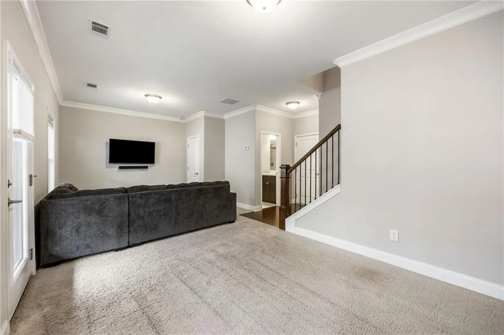 Living area with crown molding, stairs, and carpet flooring