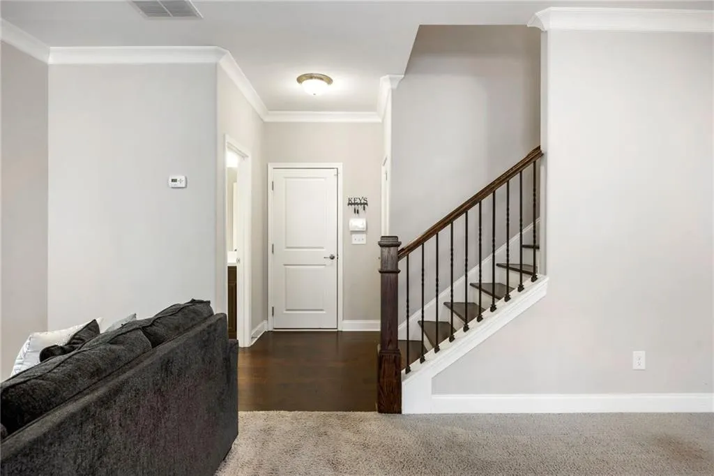 Entrance foyer with ornamental molding, stairs, dark colored carpet, and dark wood-type flooring