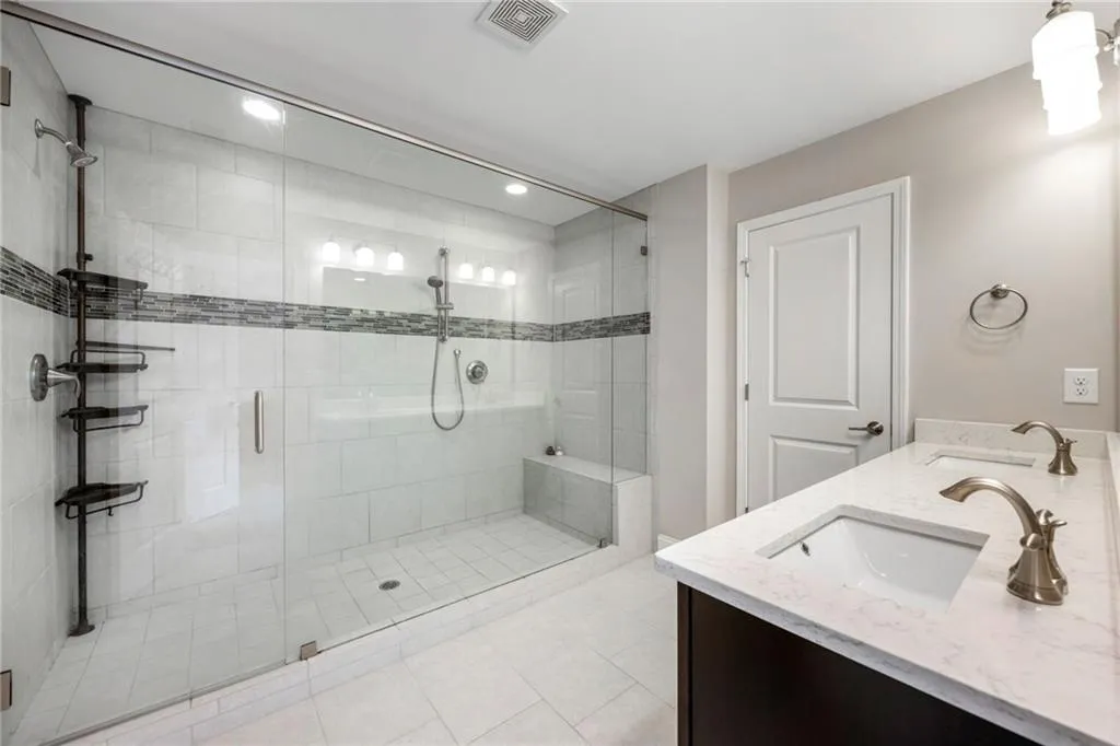 Full bath with double vanity, a shower stall, light tile patterned floors, and recessed lighting