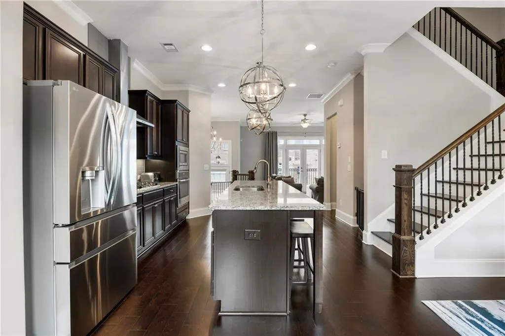 Kitchen with stainless steel appliances, a chandelier, recessed lighting, light stone countertops, and hanging light fixtures