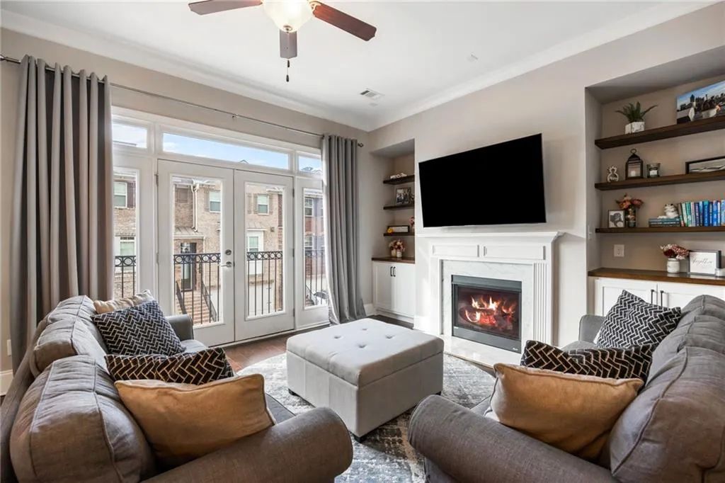 Living area featuring built in shelves, wood finished floors, a fireplace, french doors, and ornamental molding