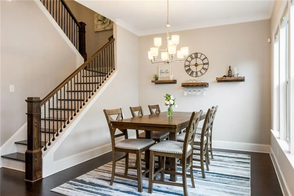 Dining area featuring dark wood finished floors, stairs, crown molding, and a chandelier