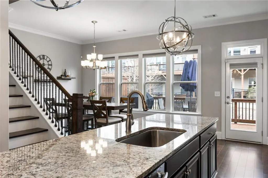 Kitchen featuring a chandelier, light stone countertops, ornamental molding, dark cabinets, and dark wood-style flooring